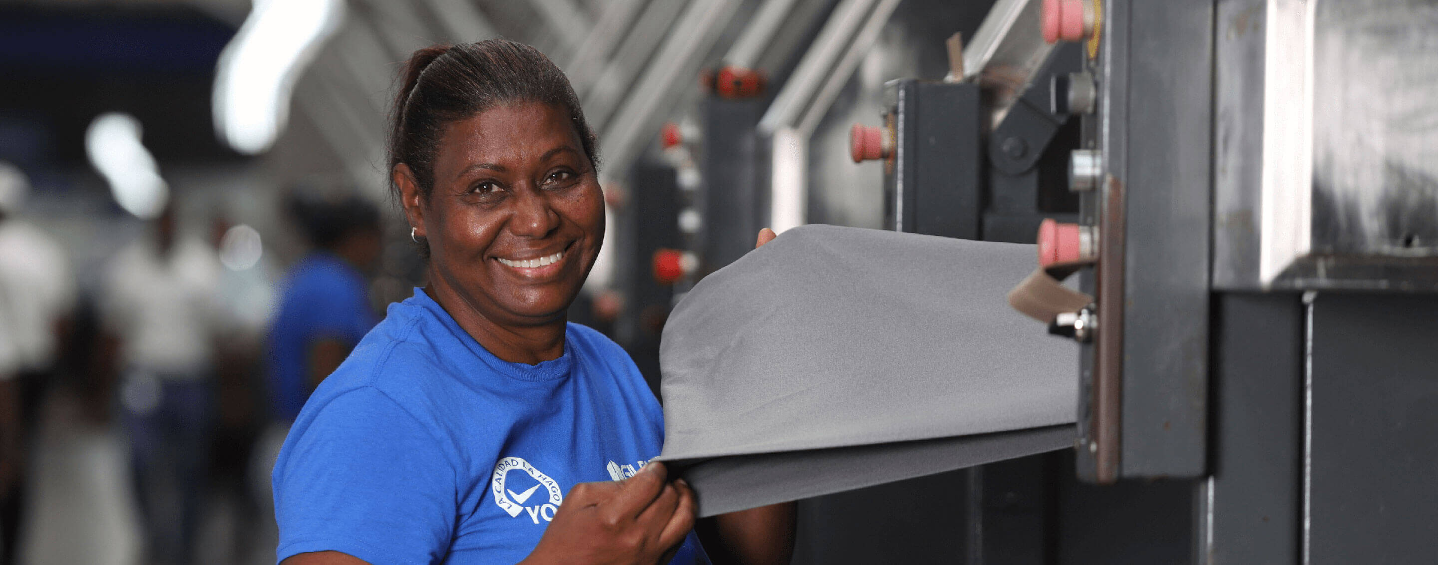 A male and female employee wearing Gildan shirts are smiling at the camera