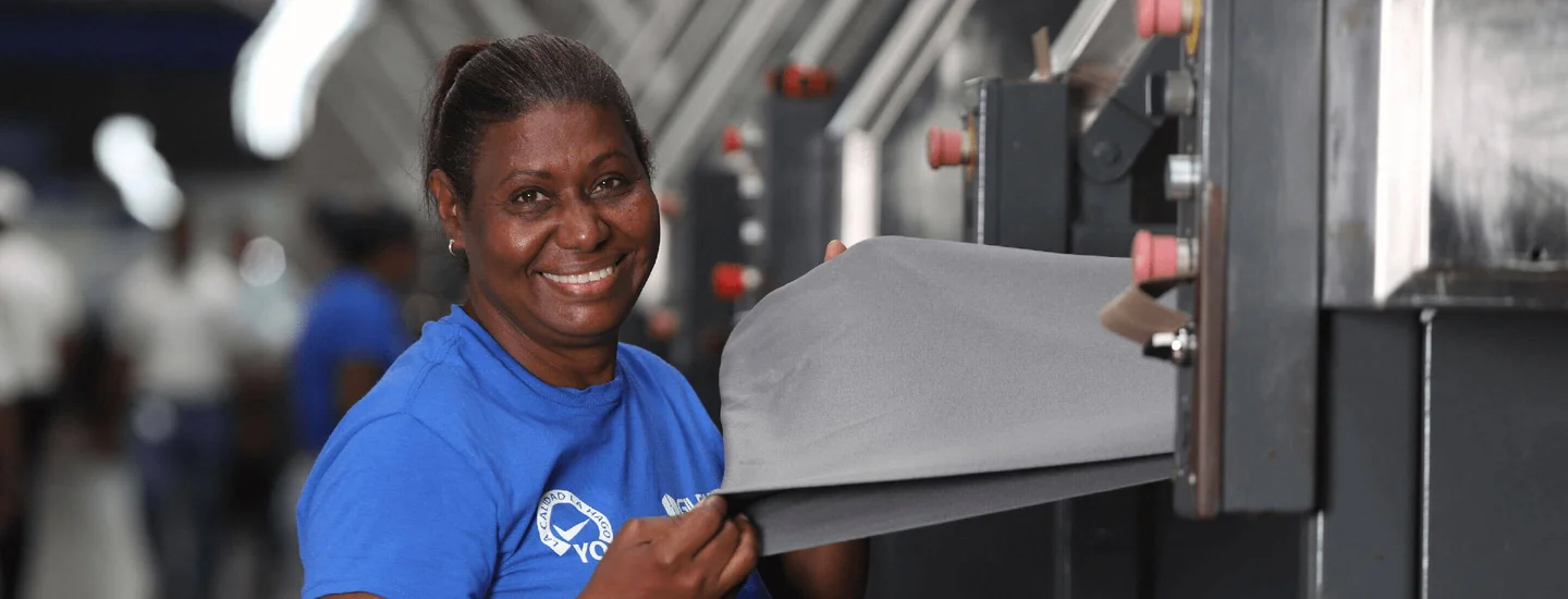 A male and female employee wearing Gildan shirts are smiling at the camera