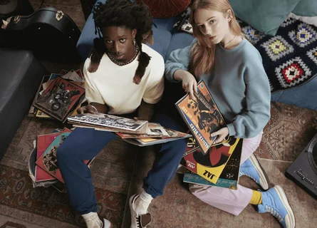 Un homme et une femme sont assis par terre et regardent la caméra en tenant des disques vinyles.