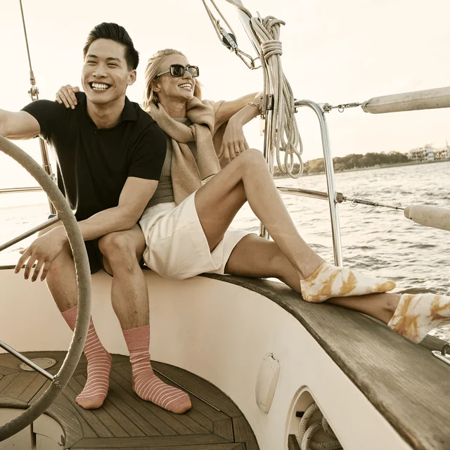 Un homme et une femme portent des chaussettes GOLDTOE sur un bateau.