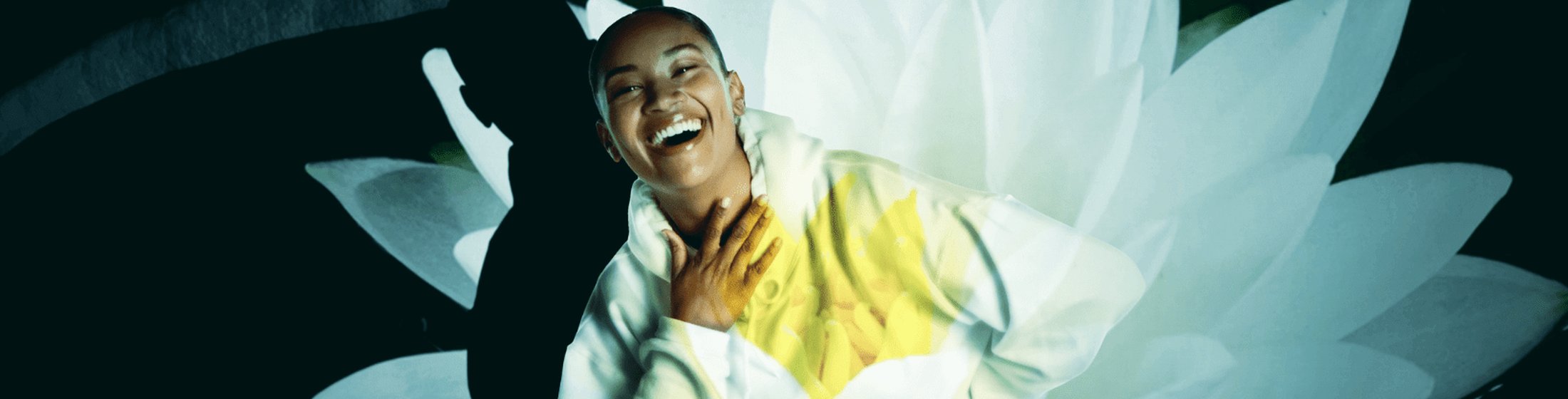 Femme en pull blanc riant avec une fleur en surimpression.