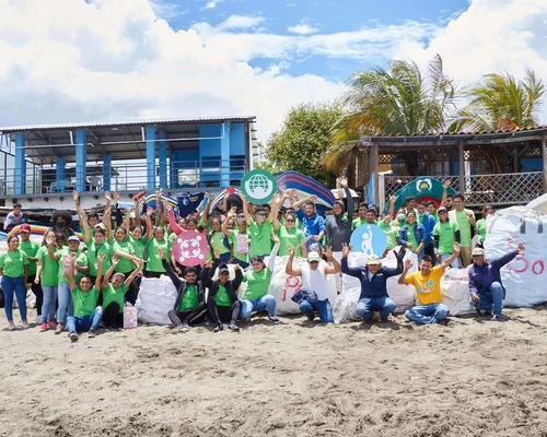 Des employés du Nicaragua se tiennent sur la plage et sourient après avoir nettoyé.