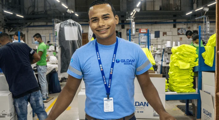 Un homme porte un cordon Gildan et s'appuie sur une table en souriant à la caméra.