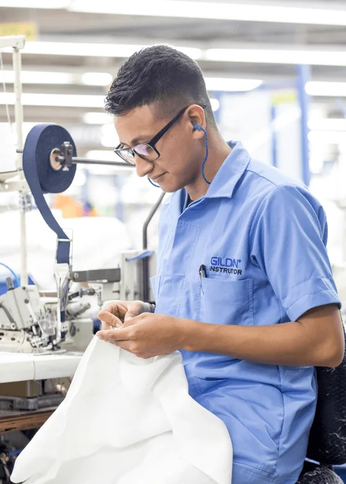 Un homme portant une chemise bleue boutonnée évalue un morceau de tissu blanc.